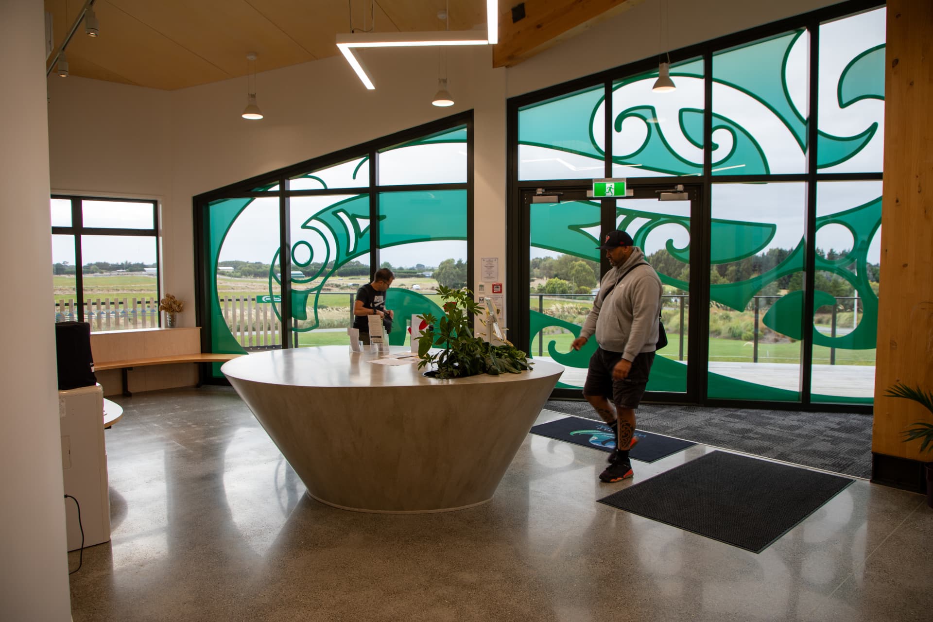 The reception area inside the marae, with large teal patterned windows